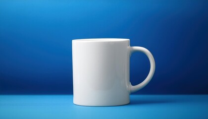 Obraz premium Blank White Coffee Mug on Blue Background The simple design and contrasting colors make it ideal for mockups, branding, and product presentations.