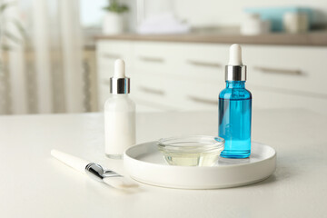 Peeling procedure. Bottles of chemical peel, bowl with liquid and brush on white table indoors