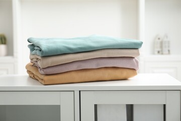 Stack of clean clothes on white dresser indoors