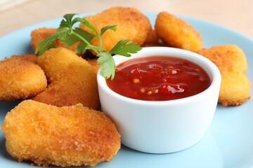 Tasty chicken nuggets with chili sauce and parsley on table, closeup