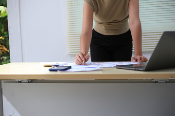 Fototapeta premium Successful Asian businesswoman sitting at desk working using laptop computer in office. Business and people concept. Businesswoman using laptop computer and working with documents.