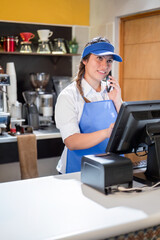 A restaurant manager takes an order over the phone which will then be handed over to a delivery person for home delivery. Vertical shot for social media.