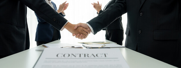 Two business executive shake hand in boardroom, sealing agreement merging two company. Handshake symbolize business partnership and cooperation. Corporate acquisition and merger concept. Shrewd