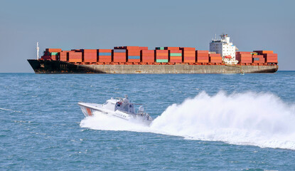 Coast Guard patrol boat rushing to the rescue container ship in the background