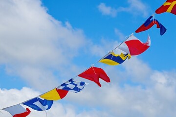 Flags for hanging. Multicolored flags in the wind against the sky. Marine signal flags.