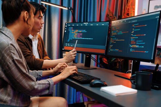 IT developers discussing with point to intelligent website development coder system running data online two screens information technology at neon light room at modern office. Infobahn.