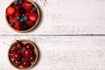 Bowl with berry mix and cherry on wooden background, Berries and cherry in a bowl, Summer berry, cherry. Top view, fruit in a wooden bowl, healthy food
