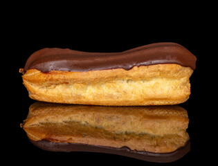 One eclair with cream, macro, isolated on black background.