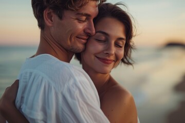 Fototapeta premium Honeymooners cuddling on the beach with love and tenderness. A Maldives beach vacationer kisses and embraces his wife from behind.