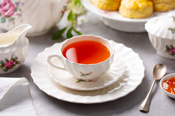 Cup of tea with scones with jam and milk. Grey background. Close up.