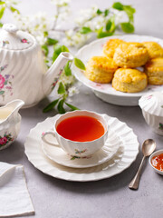 Cup of tea and teapot with scones with jam, clotted cream. Grey background.