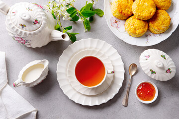 Cup of tea with scones with jam, clotted cream. Grey background. Top view.