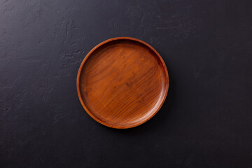 Round wooden plate, cutting board. Grey background. Copy space. Top view.