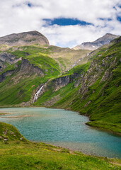 An idyllic landscape of snow capped peaks, mountains covered with green grass and a blue lake. Grossglockner, the highest mountain in Austria. Hohe Tauern National Park