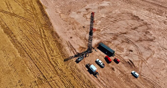 Footage around the site for gas production. Few cars stand near the truck with high derrick for drilling natural resources. Aerial perspective.