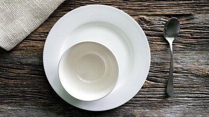 Serene table setting with white plates and silver spoon on rustic wooden surface
