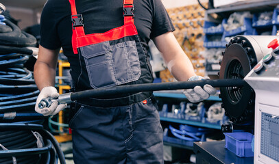 Manufacturing process Worker crimps pressure hydraulic hose with fitting on machine