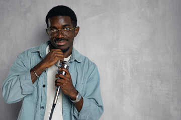 Man singing hit with open mouth in retro microphone. Portrait of handsome attractive african american singer on grey background studio