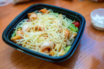 vibrant shrimp salad in a sleek plastic dish, showcasing fresh greens, succulent shrimp, and a drizzle of tangy dressing, epitomizing convenience and flavor for busy food lovers
