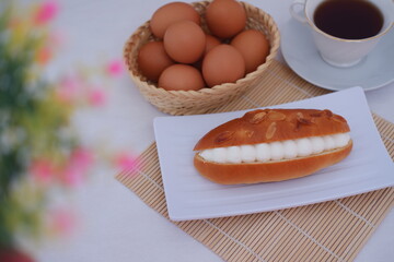 Eclair on a white plate with bamboo mat, top view.