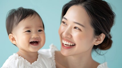 Tender studio shot of an Asian mother admiring her smiling baby, reflecting their deep emotional connection and affection.
