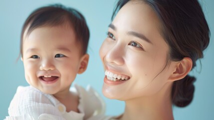 Gentle smiles of an Asian mother and her baby, radiating warmth and affection in a light-filled studio.