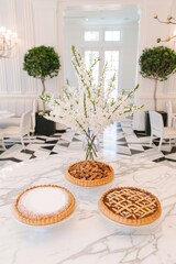 Three different types of pies are displayed on a marble countertop. The pies are arranged in a way that they are all visible and easily accessible. The setting is elegant and sophisticated