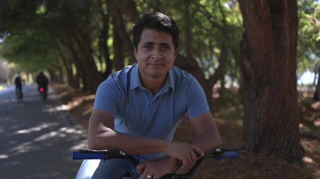 Portrait of a mexican man smiling and posing with a bicycle outdoors