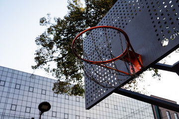 A vibrant urban basketball hoop stands out against the backdrop of modern architectural structures...