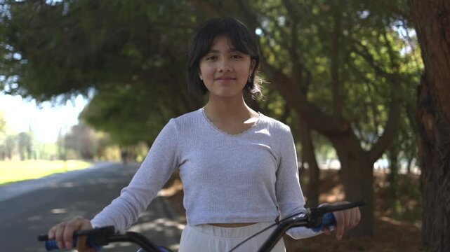 Portrait of a Mexican teenager posing with a bicycle outdoors