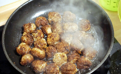 Königsberger Klopse in a frying pan with olive oil, heat and highest setting on the stove, frying meat on the stove, fat and dirt when cooking, preparing dishes and food, cooking yourself,
