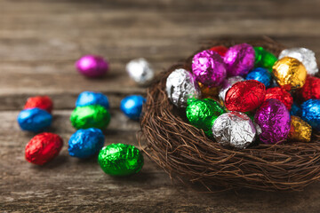 COLOURED EASTER EGGS. Easter celebration concept. Happy Easter. Chocolate sweet eggs. Candies on textured wooden table. Space for text.Copy space