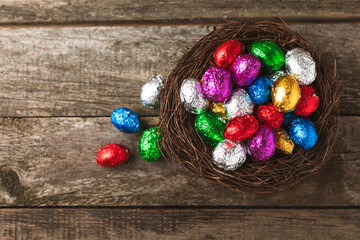 COLOURED EASTER EGGS. Easter celebration concept. Happy Easter. Chocolate sweet eggs. Candies on textured wooden table. Space for text.Copy space