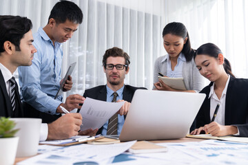 Diverse group of business analyst team analyzing financial data report paper on office table. Chart and graph dashboard by business intelligence analysis for strategic marketing planning Meticulous