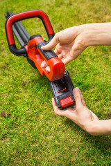 Hand changing accumulator - Teenager changes rechargeable battery in electric garden tool