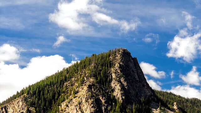 Timelapse video of a mountain top bathed in sunshine with clouds streaming by.