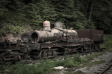 Old abandoned locomotive on train tracks in the woods