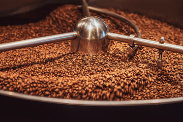 Close-up of freshly roasted coffee beans cooling in industrial coffee roaster, highlighting coffee production process
