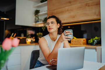 Young caucasian woman working from home on laptop