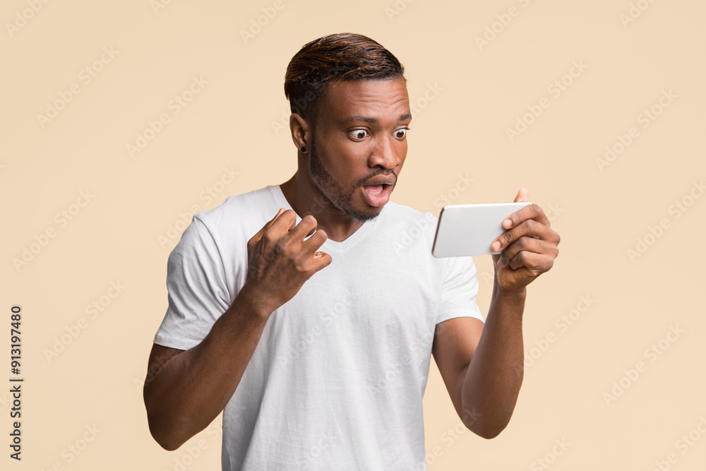 Poster shocking news. amazed afro guy looking at smartphone reading message standing over yellow background