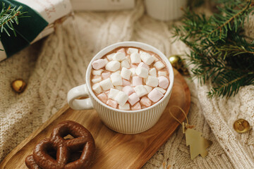 Christmas mood. Cup of hot chocolate with marshmallows and cookies, christmas ornaments and gift, cozy knitted sweater and fir branches. Winter hygge wallpaper