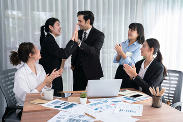 Group of happy businesspeople in high five gesture and successful efficient teamwork. Diverse race office worker celebrate after made progress on marketing planning in corporate office. Habiliment