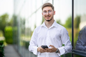 young man beside a glass building with mobile 