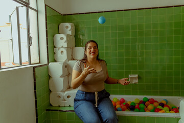 Mujer latina sentada en una tina de baño con pelotas de colores