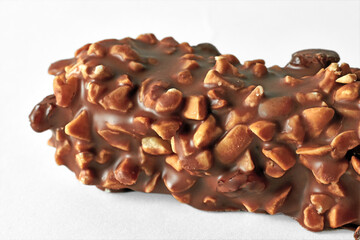 Piece of sweet bar with nuts covered with chocolate isolated on white background