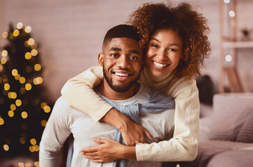 Christmas eve. Loving couple embracing and smiling to camera in front of Christmas tree