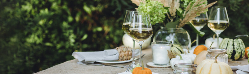 Fall still-life. Orange pumpkins, dry flowers and candles on linen tablecloth. Dinner table outdoors in the garden. Cozy autumn concept., simple handmade decoration, countryside style banner