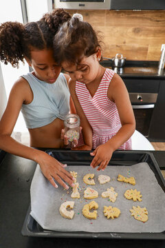 Children decorating cookies together in modern kitchen