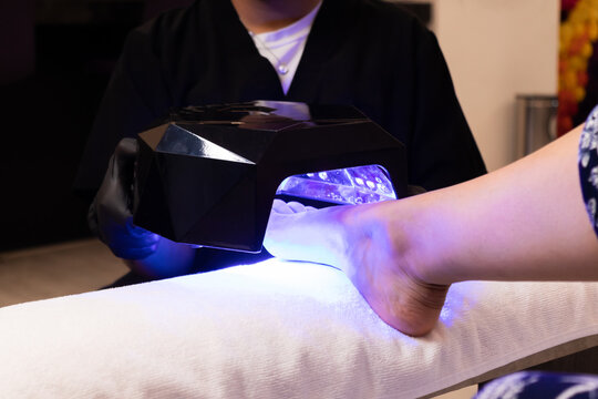 Pedicure session using modern UV light device in wellness center