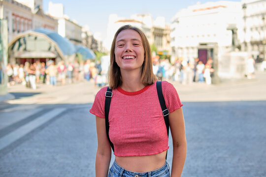 Young woman laughing joyfully in a busy city square